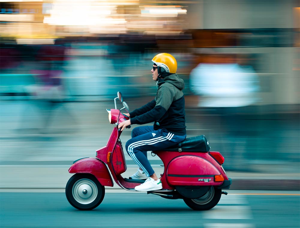 Bild von einem roten Moped und Fahrer mit gelben Helm